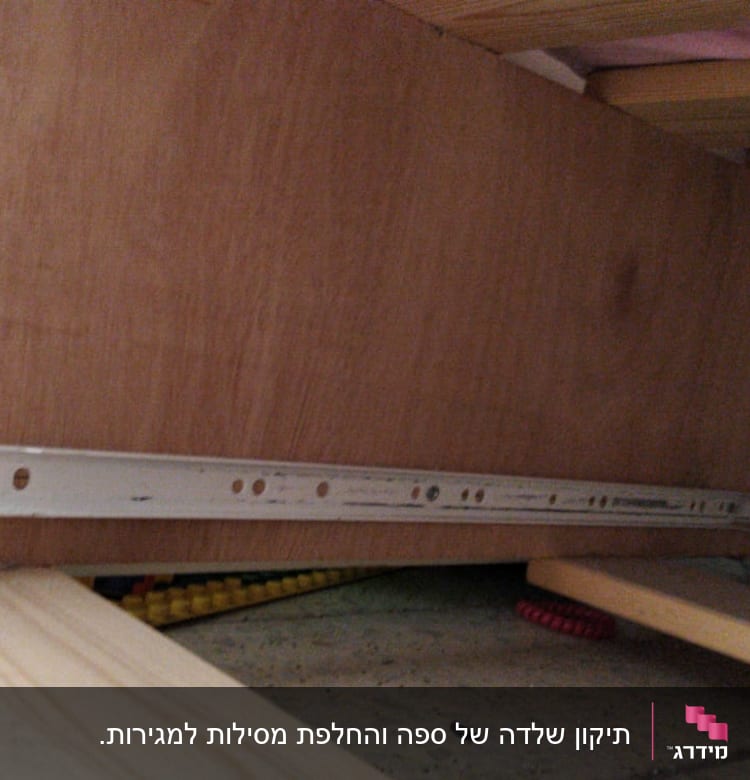 מסילת מתכת מחוברת ללוח עץ מתחת למיטה